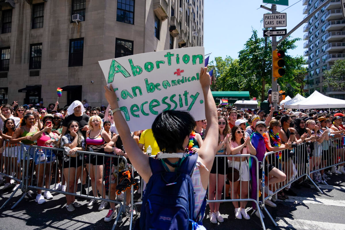 A reveler holds a sign showing support of abortion rights as she marches down Fifth Avenue during the annual NYC Pride March, Sunday, June 26, 2022, in New York. The U.S. Supreme Court's decision to end constitutional protections for abortion has cleared the way for states to impose bans and restrictions on abortion — and will set off a series of legal battles. (AP Photo/Mary Altaffer)