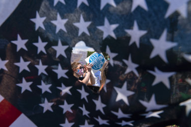 Abortion rights activists are seen through a hole in an American flag as they protest outside the Supreme Court in Washington, Saturday, June 25, 2022. The Supreme Court’s decision to overturn national protections for abortion has set off a contest between Democratic and Republican lawmakers over whose policies would do more to help vulnerable mothers and children. It's a key issue going into the midterm elections.