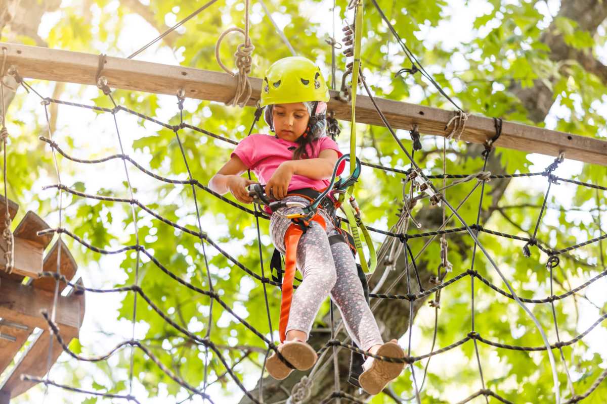 Girl climbing in high rope course enjoying the adventure