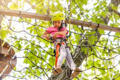 Girl climbing in high rope course enjoying the adventure