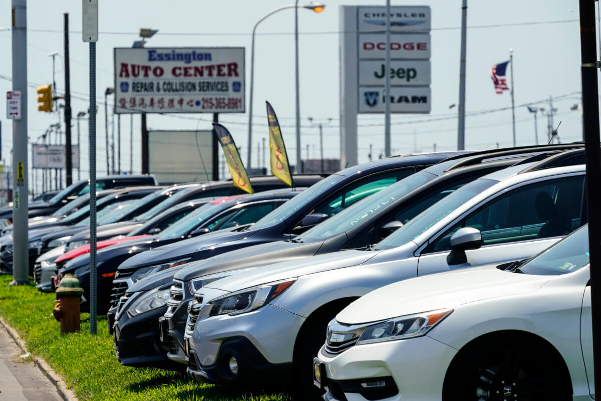 Used cars for sale are parked roadside at an auto lot in Philadelphia.