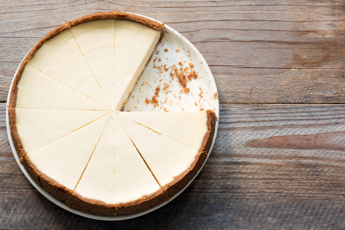 New York Cheesecake or Classic Cheesecake sliced on rustic wood, top view