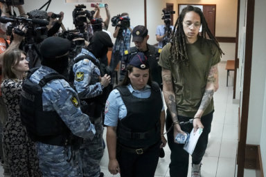 WNBA star and two-time Olympic gold medalist Brittney Griner is escorted in a court room prior to a hearing, in Khimki just outside Moscow, Russia.