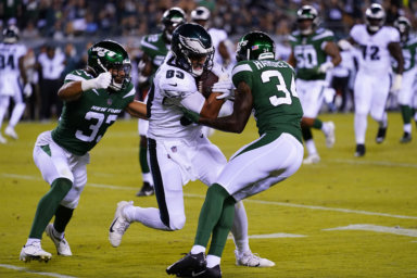 An Eagles player runs with the ball between Jets' Justin Hardee and Elijah Riley during the 2nd half of a preseason game on Aug. 12.