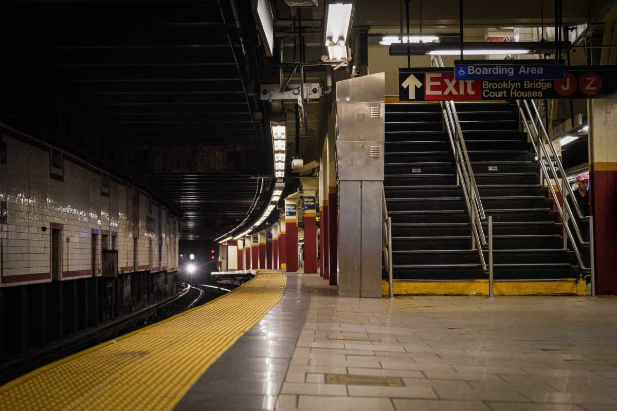 A train pulls into a barren subway platform.