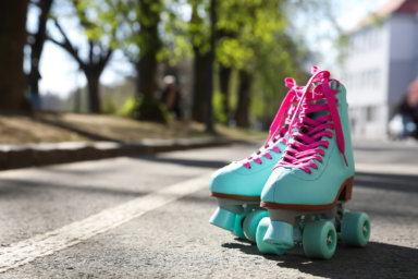 Stylish pink roller skates outdoors on sunny day. Space for text