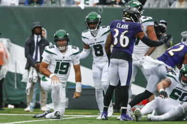 Jets' Elijah Moore helps up quarterback Joe Flacco after Flacco threw an interception during the first half against the Ravens.