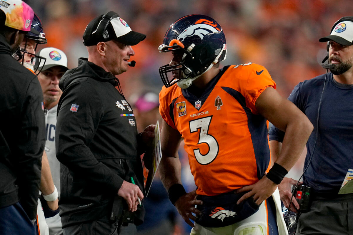 Broncos quarterback Russell Wilson, who will sit against the Jets, talks with head coach Nathaniel Hackett.