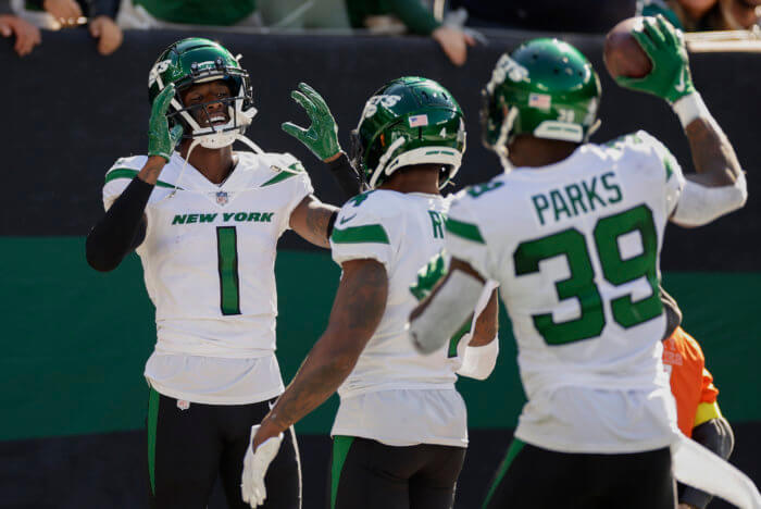 Jets cornerback Sauce Gardner (1) celebrates with teammates after intercepting the ball against the Miami Dolphins.