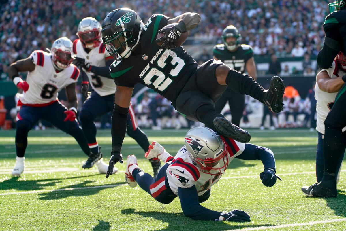 Jets running back James Robinson is upended by New England Patriots cornerback Jack Jones.
