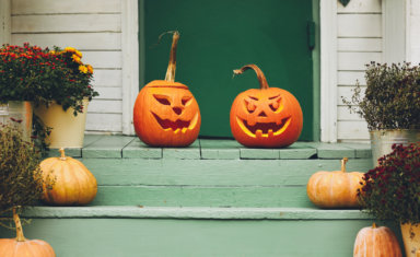 House with halloween orange pumpkin decoration, jack o lanterns with spooky faces on porch