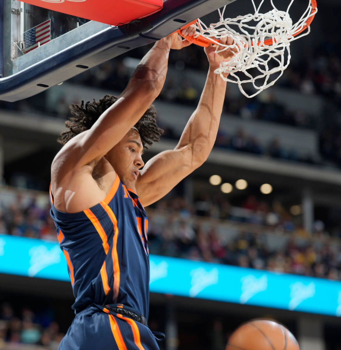 Knicks center Jericho Sims hangs on the rim after dunking the ball for a basket against the Denver Nuggets.