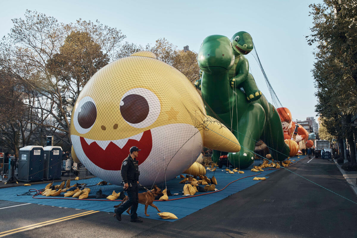 Police walk by inflated helium balloons of Baby Shark and Sinclair's Dino on Wednesday, Nov. 23, 2022, in New York