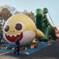Police walk by inflated helium balloons of Baby Shark and Sinclair's Dino on Wednesday, Nov. 23, 2022, in New York