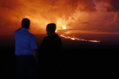Spectators watch the lava flow down the mountain from the Mauna Loa eruption in Hawaii