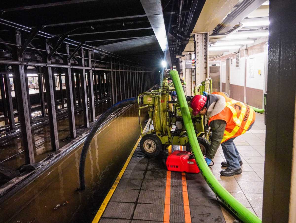An MTA employee works to clear flooding at Canal Street subway station after a water main break affected transit.