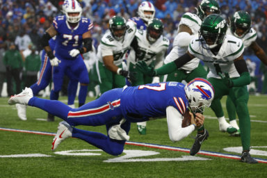 Buffalo Bills quarterback Josh Allen, front, lunges with the ball under pressure from New York Jets cornerback Sauce Gardner.