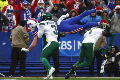 Buffalo Bills tight end Dawson Knox, behind top, jumps into the end zone past New York Jets safety Jordan Whitehead and cornerback Sauce Gardner for a touchdown.