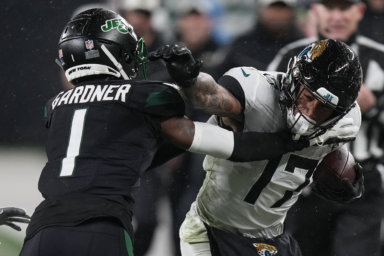 Jaguars tight end Evan Engram stiff-arms Jets cornerback Sauce Gardner.