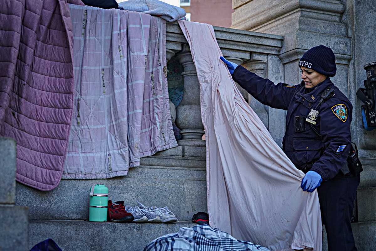 FILE: An officer removes items from a homeless encampment.