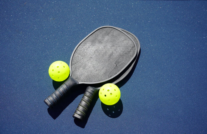 Two pickleball paddles and two pickleballs on court