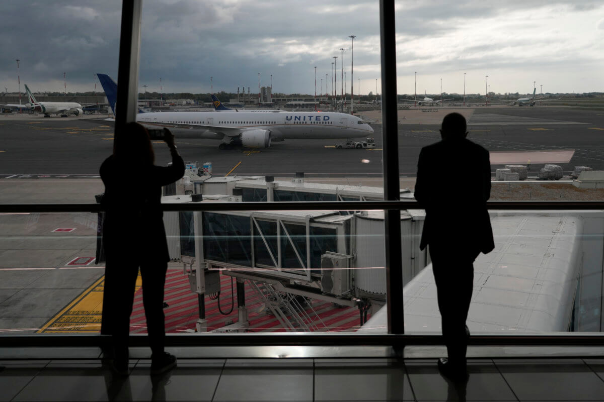 People look from a window of Fiumicino's Leonardo Da Vinci airport, near Rome, on Nov. 8, 2021.. COVID travel. Travelers whose package tours were ruined by the imposition of restrictions to combat the COVID-19 pandemic may be entitled to at least a partial refund, the European Union's highest court said