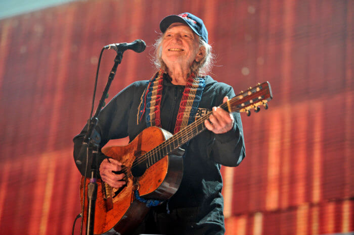 Willie Nelson playing a guitar on stage.