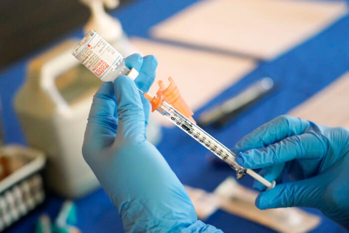A nurse prepares a syringe of a COVID-19 vaccine