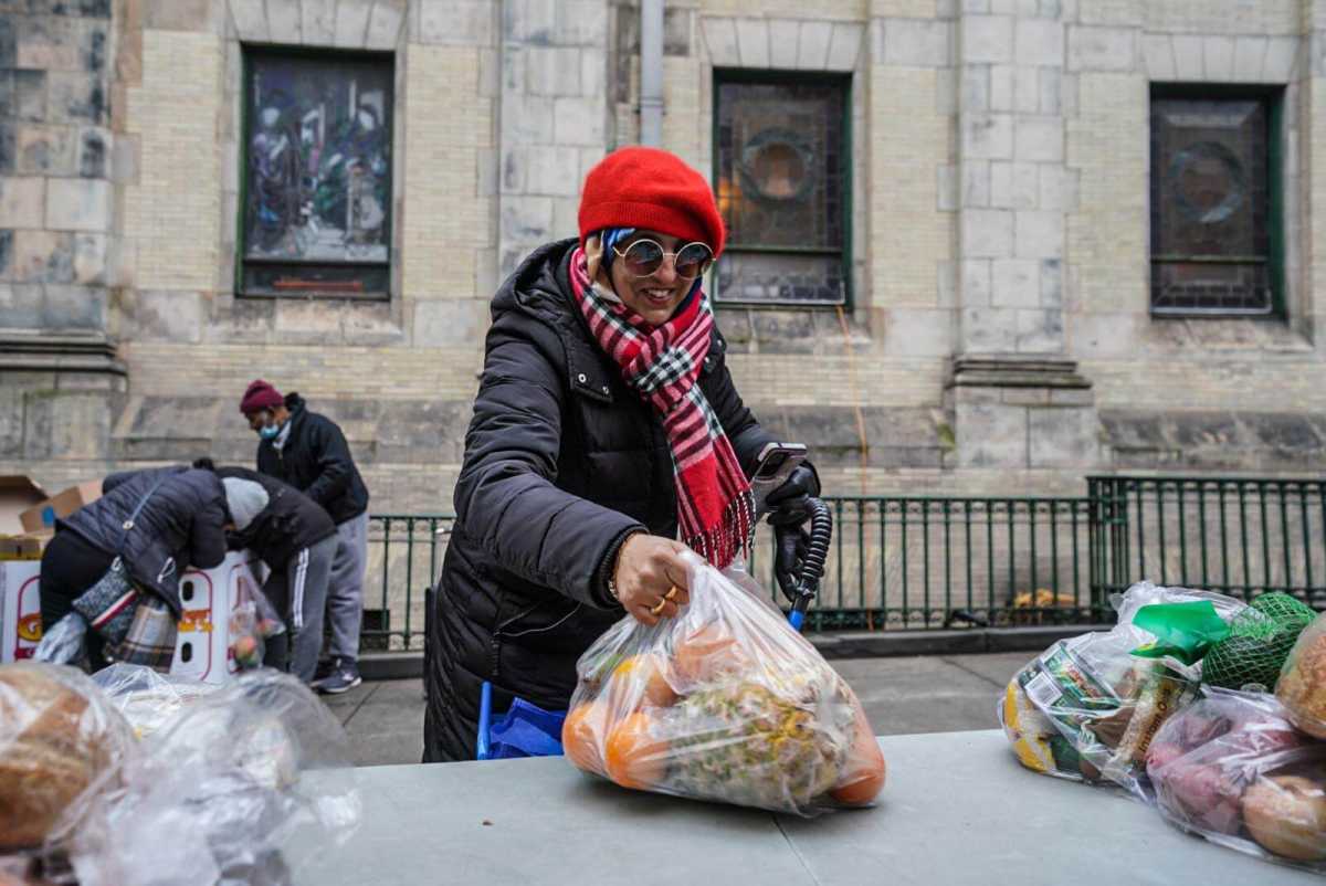 A woman is picking up the lid of the food container.