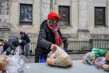 A woman is picking up the lid of the food container.