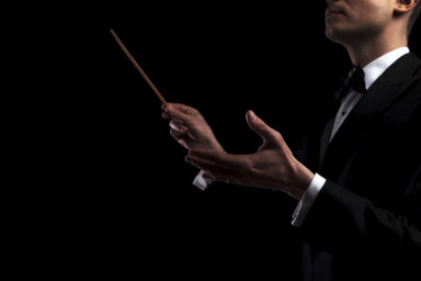 portrait of young orchestra conductor performing with a baton