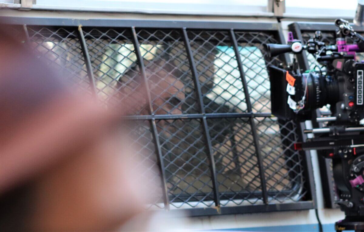 Joaquin Phoenix, playing Joker, smiles from a police van on the set of Joker 2, "Joker: Folie à Deux" (Photo by Michael Dorgan)