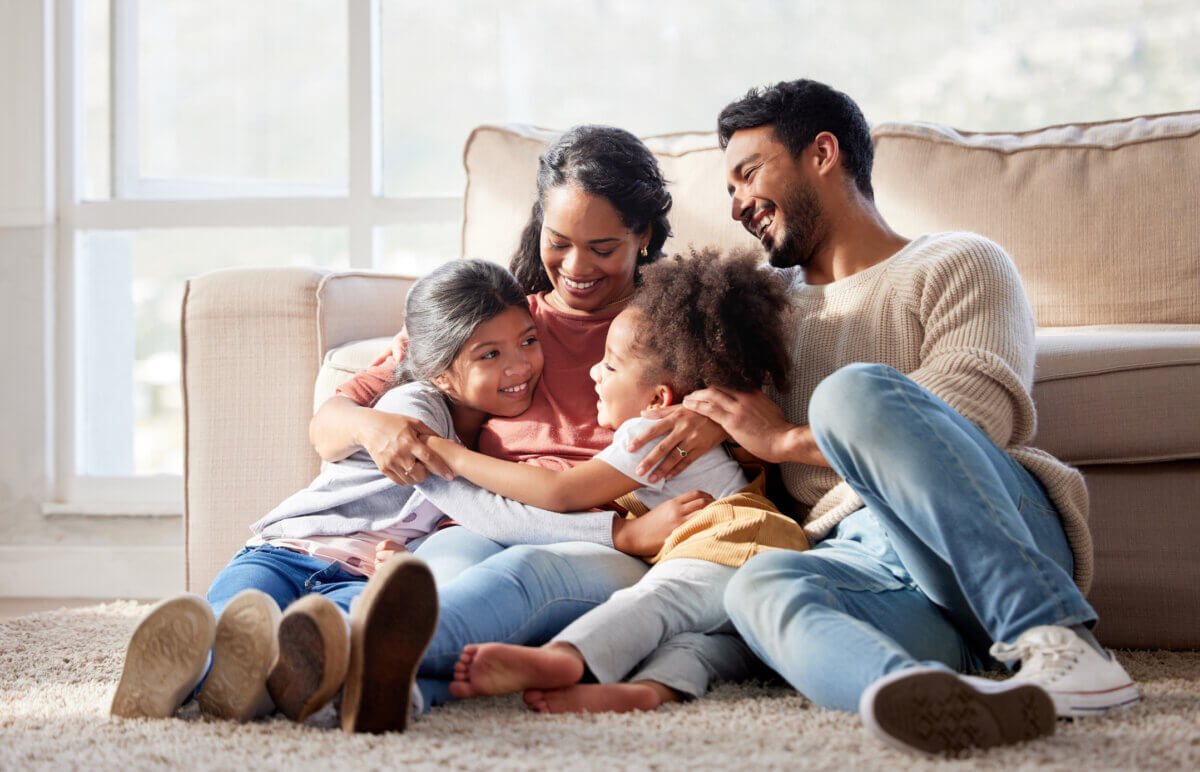 Affectionate and loving mixed race family sitting together. Happy family with two daughters hugging their mother and bonding at home. Two little girls enjoying a happy childhood with mom and dad