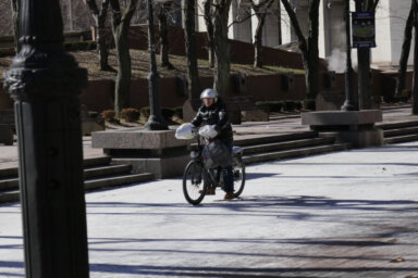 A delivery cyclist on an e-bike in a New York City park.
