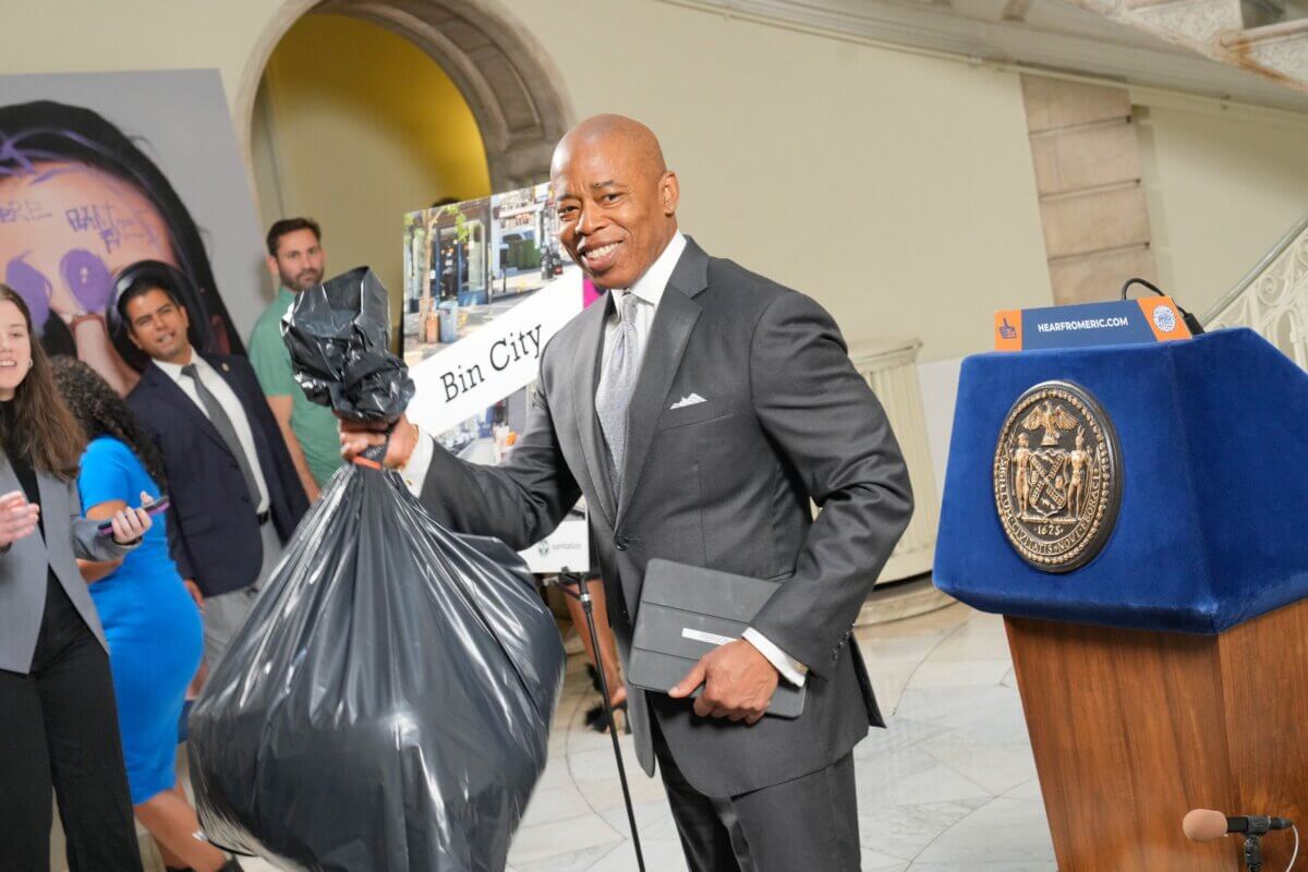 Mayor Eric Adams holding a trash bag at City Hall.