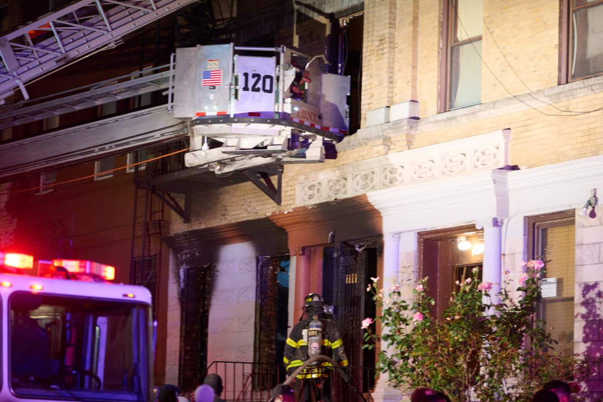 Brooklyn firefighters on ladder reaching burned home