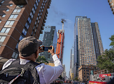 A bystander takes photos of a crane collapse in Midtown