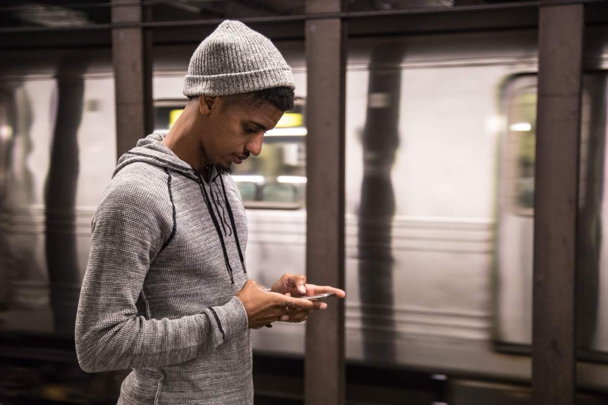 A man looking at his phone on a subway platform.