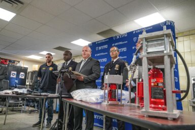 Queens police with items seized in drug den raid