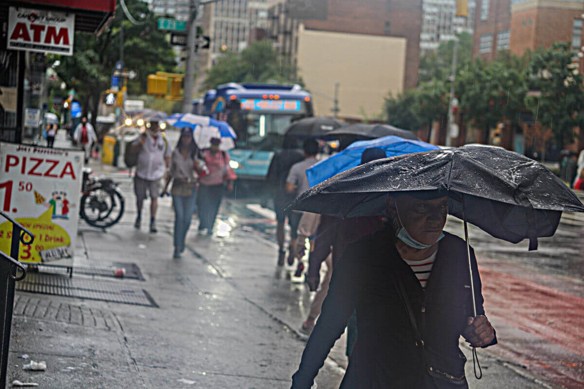 Person walking with broken umbrella during Henri