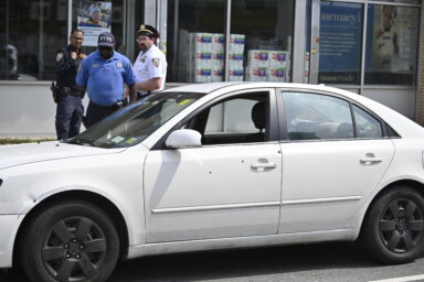 Police officers near a bullet-riddled car after two people shot in Brooklyn