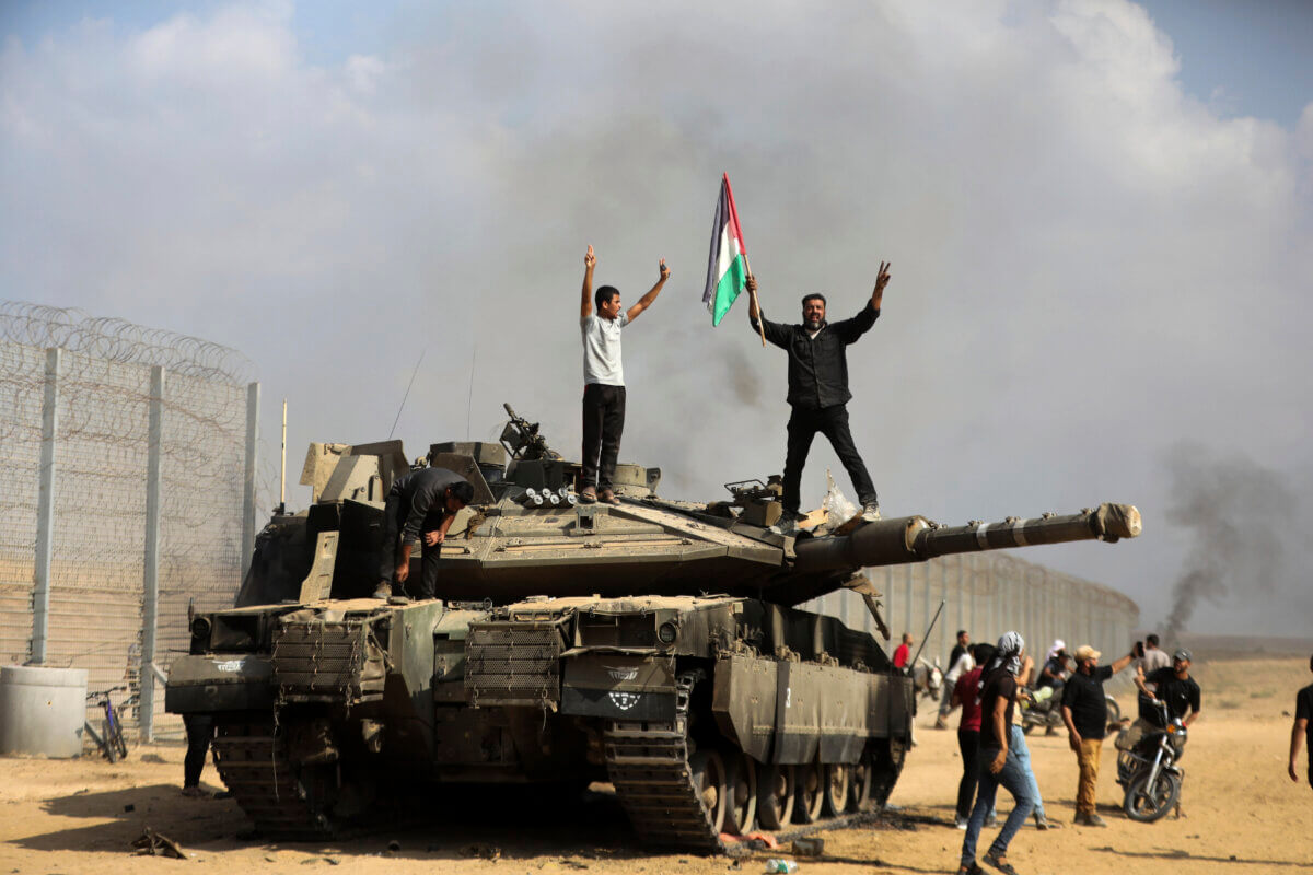Hamas fighters in Gaza Strip stand on destroyed Israeli tank