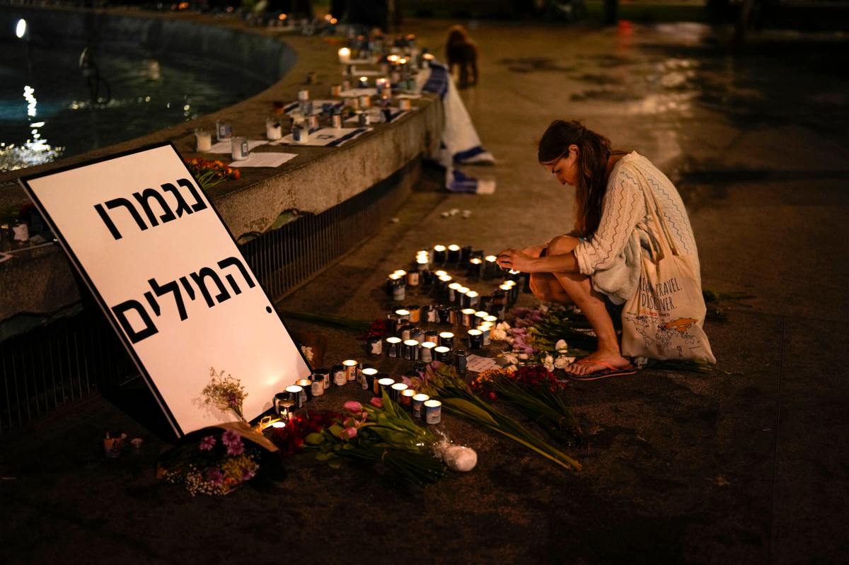 A woman lights candles in honor of victims of the Hamas attacks during a vigil at Dizengoff square in central Tel Aviv,
