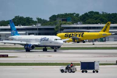 A JetBlue Airways Airbus A320, left, passes a Spirit Airlines Airbus A320 as it taxis on the runway, July 7, 2022, at the Fort Lauderdale-Hollywood International Airport in Fort Lauderdale, Fla.
