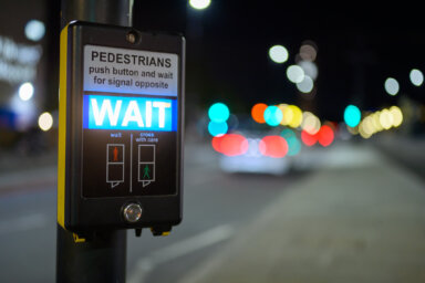 Pedestrian crossing button and illuminated wait sign with out of focus traffic in the background