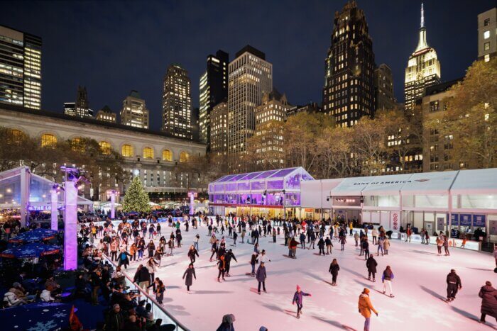 Skaters on the ice skating rink at night at Bank of America Winter Village at Bryant Park.
