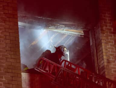 A firefighter works in a fourth floor NYCHA apartment during a two alarm fire in Brooklyn where six civilians and a firefighter were hurt on Monday evening.