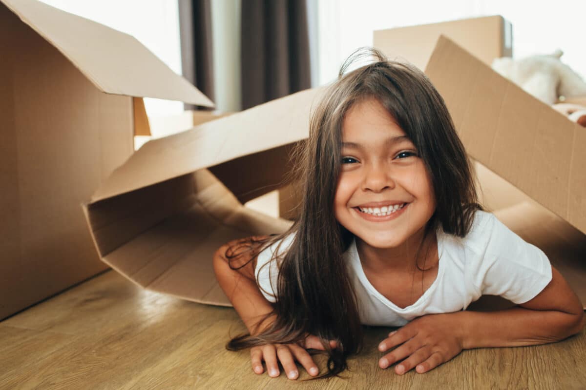 little girl playing with Cardboard Box, into her new house.