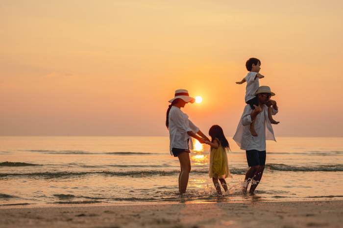 Happy asian family that enjoys beach activities during the summer holidays. parent and children enjoy the sunset sea on beach.Holiday travel concept, Summer vacations.