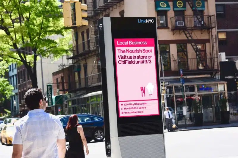 A LinkNYC kiosk showing an advertisement for The Nourish Spot in Queens.